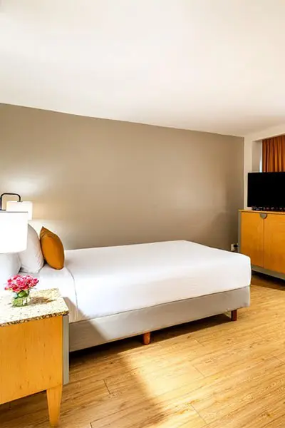 Habitaci&oacute;n de hotel con cama doble y mesa de noche con flores