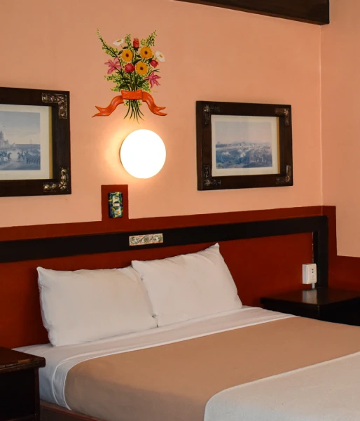 Habitaci&oacute;n de hotel con cama, pared naranja y cuadros decorativos