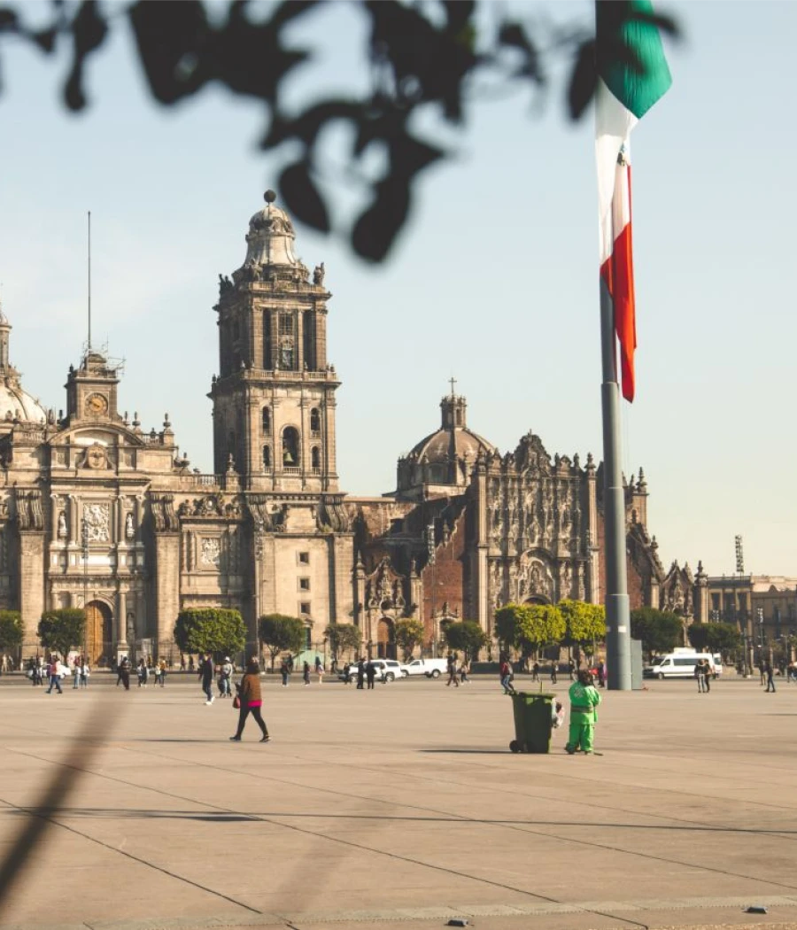 Plaza frente a la catedral, bandera mexicana y turistas en Ciudad de México