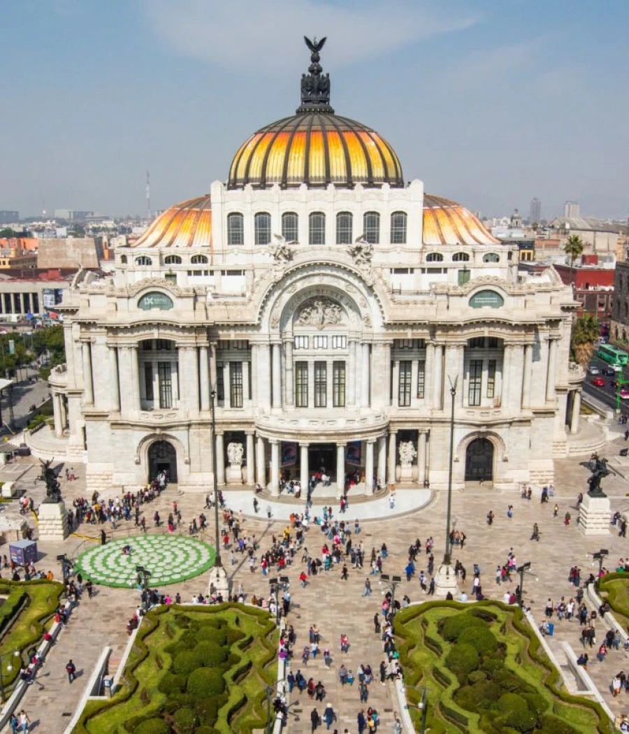 Fachada del Palacio de Bellas Artes con cúpulas doradas y visitantes.