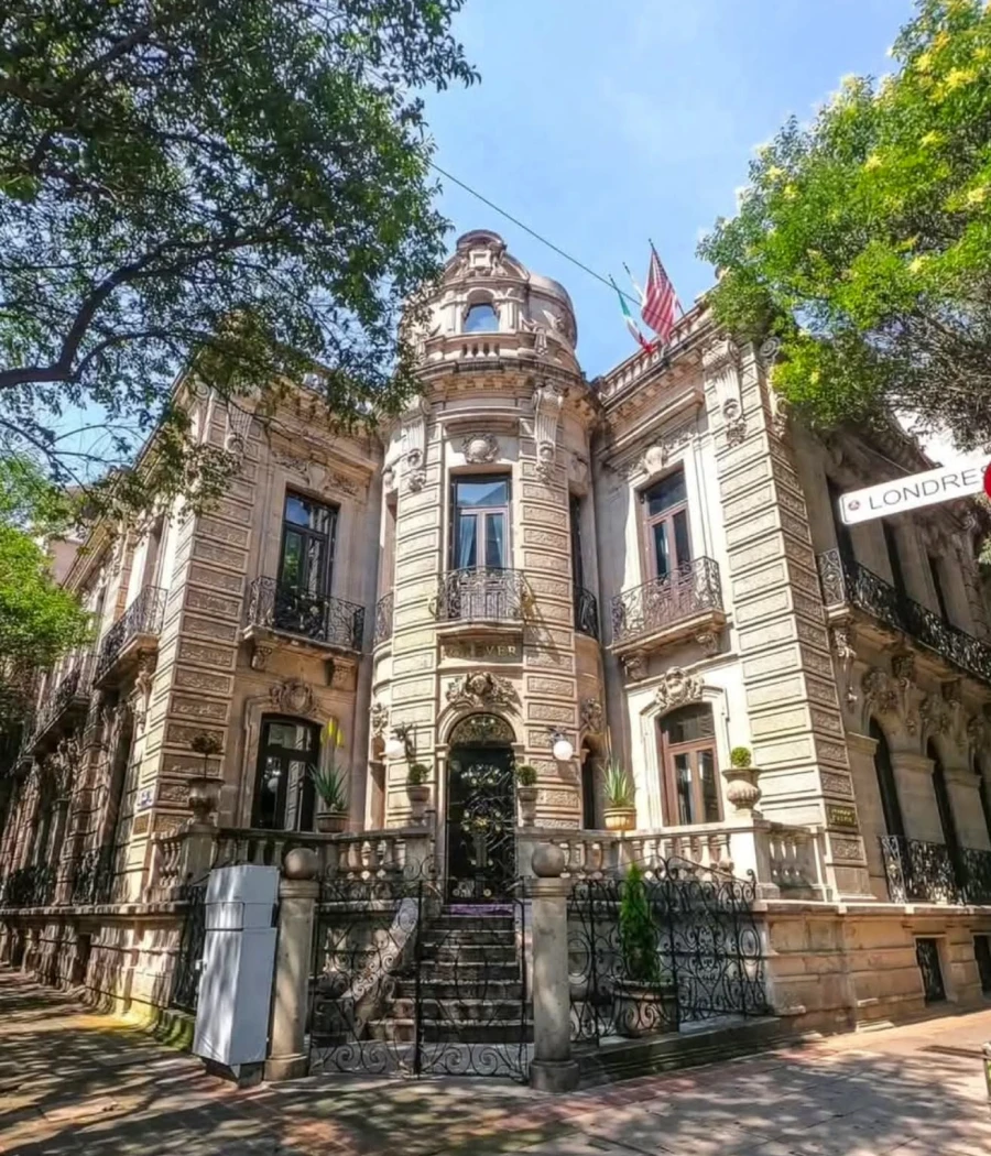 Fachada histórica con torre redonda y bandera estadounidense, entre árboles.