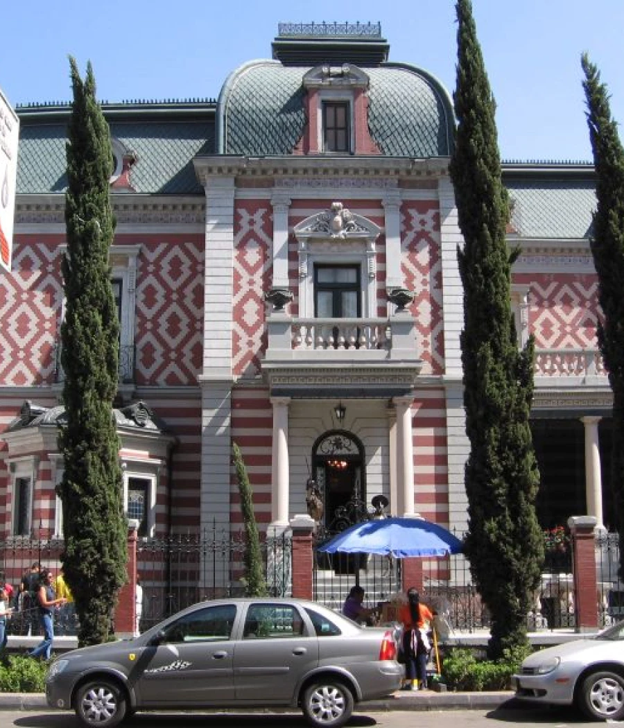 Fachada de un edificio histórico con cúpula y cipreses alrededor