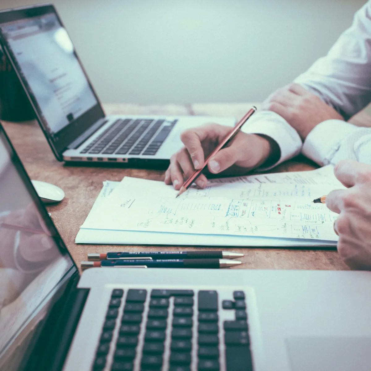 Personas revisan planos y toman notas frente a una laptop y bol&iacute;grafos