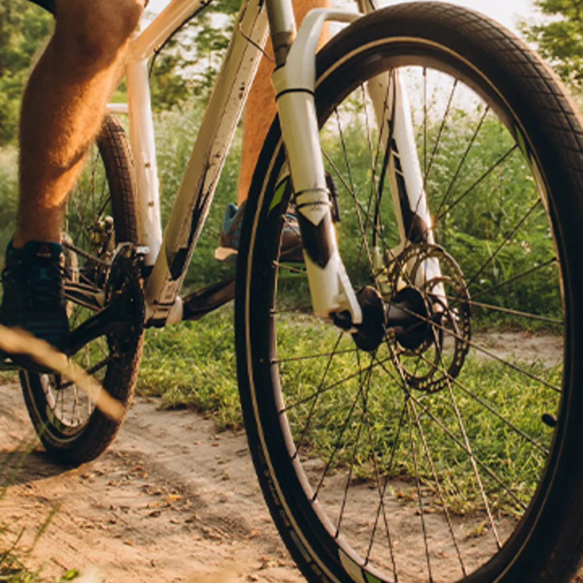 Primer plano de bicicleta con neum&aacute;ticos y rueda delantera en camino rural