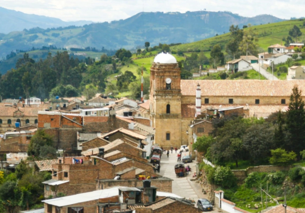 Pueblo andino con iglesia de c&uacute;pula blanca, calles y monta&ntilde;as al fondo