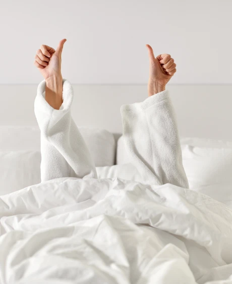 Casal deitado na cama, com as m&atilde;os em sinal de for&ccedil;a (punhos fechados)
