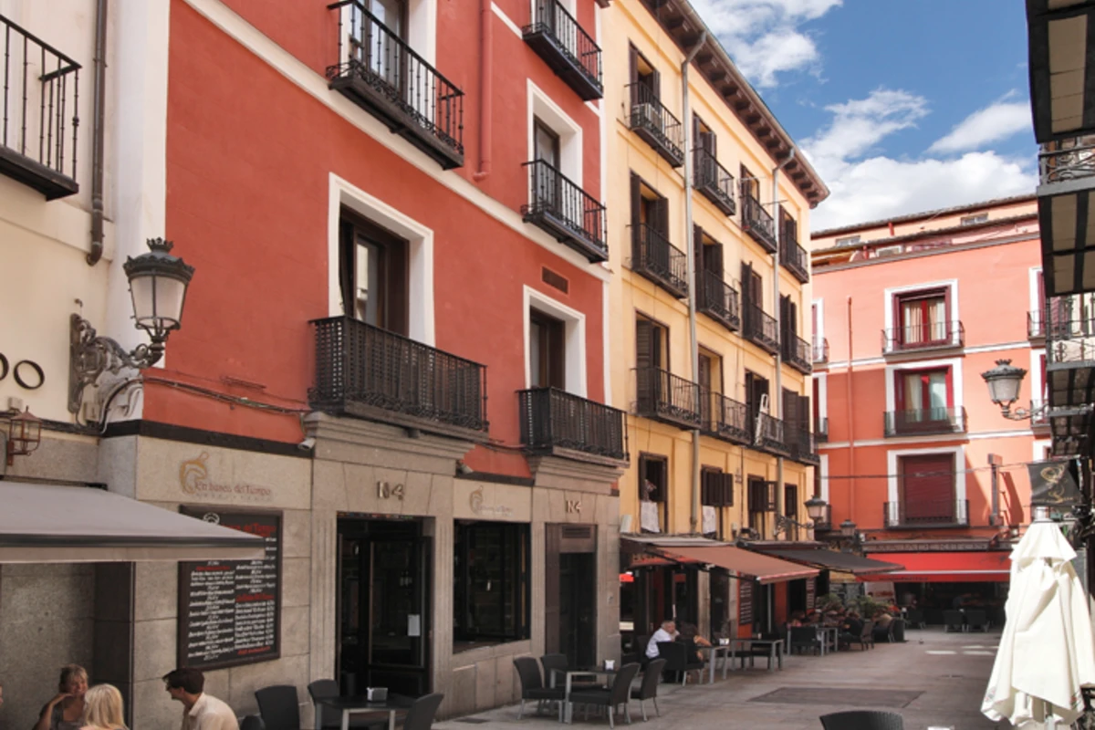 Calle con edificios de colores y terrazas, balcones y lámparas de farol.