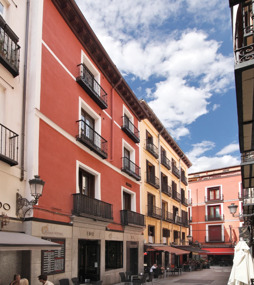 Calle con edificios de colores y balcones, cielo nublado al fondo.