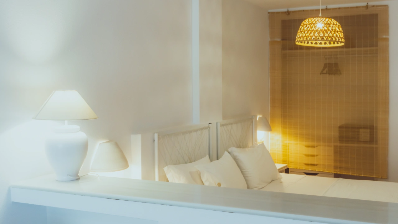 Dormitorio luminoso con cama, l&aacute;mparas de techo y mesa de luz blanca