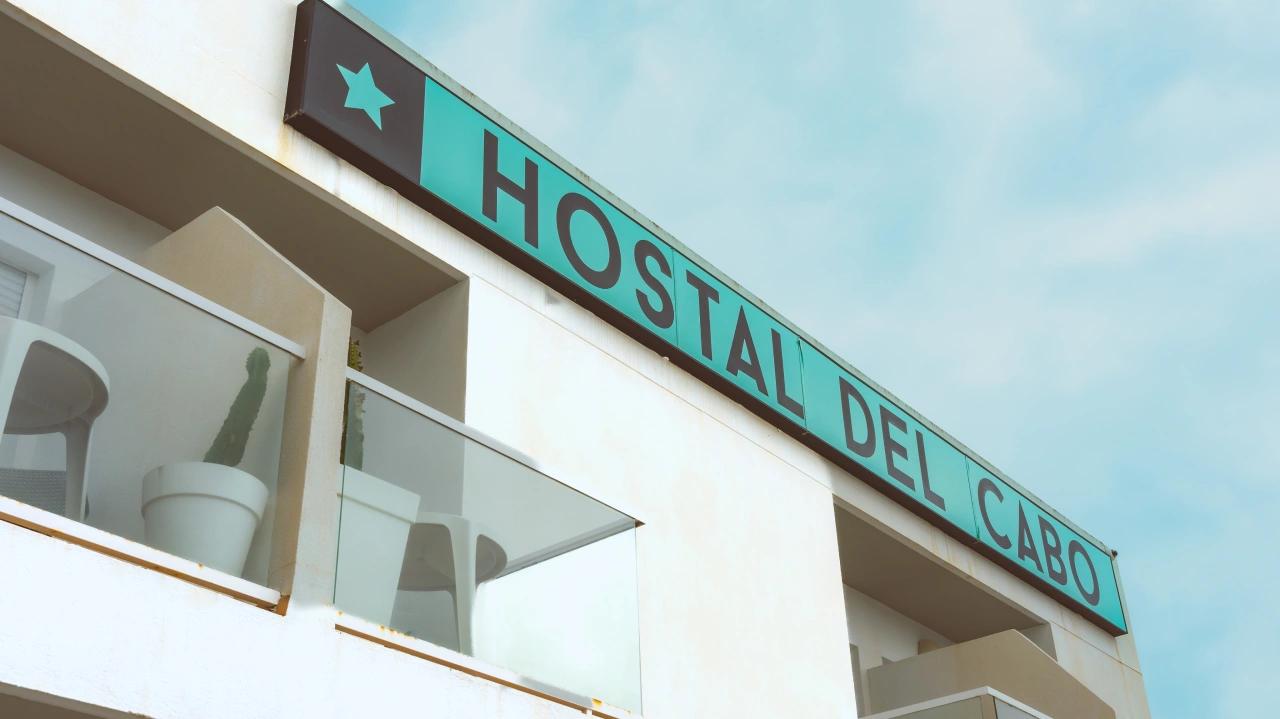 Cartel luminoso de &ldquo;HOSTAL DEL CABO&rdquo; en la fachada de un edificio