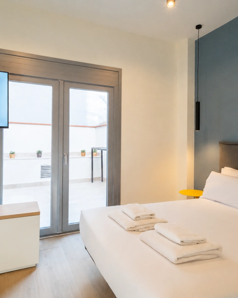 Dormitorio moderno con cama, cortinas y persianas, luz tenue y terraza al fondo