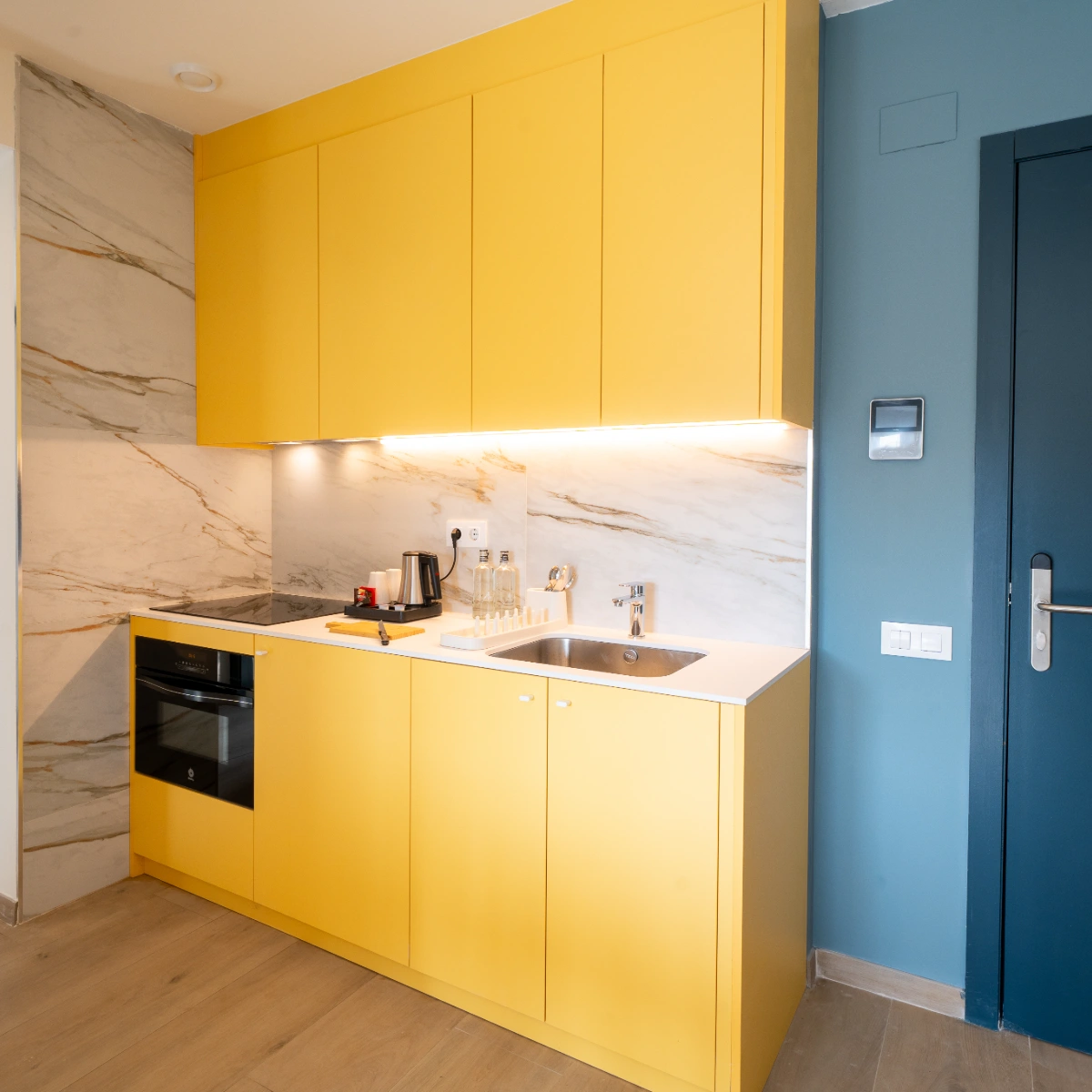 Cocina moderna con muebles amarillos y encimera con fregadero y puerta azul