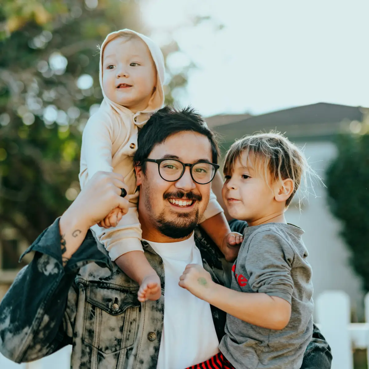 Padre con dos ni&ntilde;os peque&ntilde;os, al aire libre, sonriendo juntos