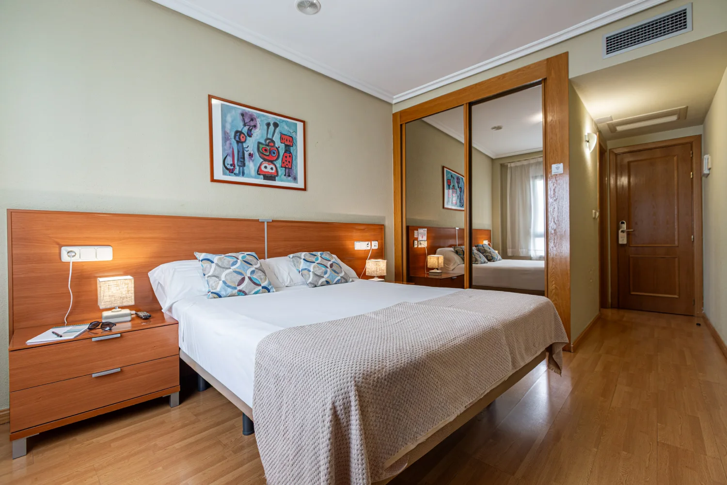 Dormitorio con cama doble, mesita de noche y cuadro infantil en la pared