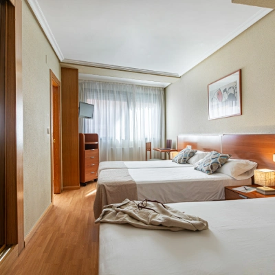 Dormitorio con camas, ventana y colcha sobre el suelo