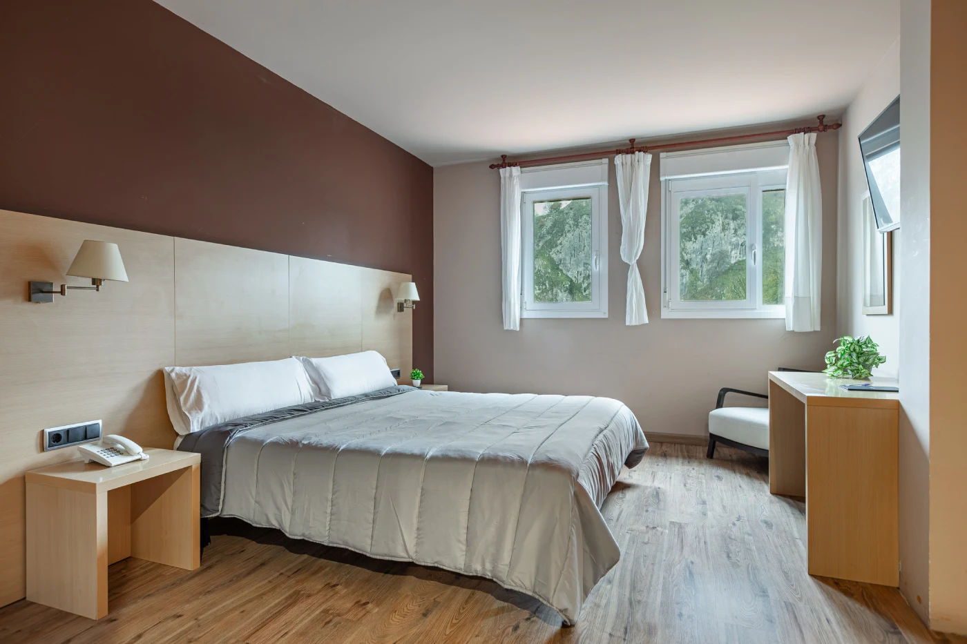 Dormitorio moderno con cama, cortinas blancas y ventanas con vista al jard&iacute;n