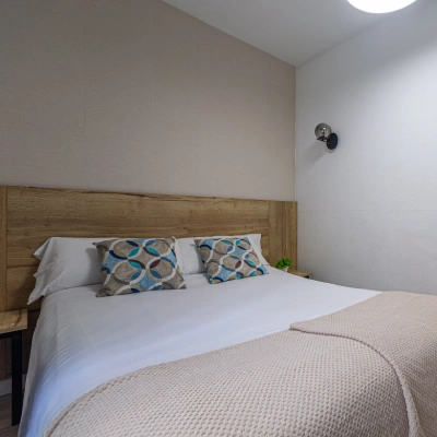Dormitorio moderno con cama doble y almohadones con estampado geom&eacute;trico