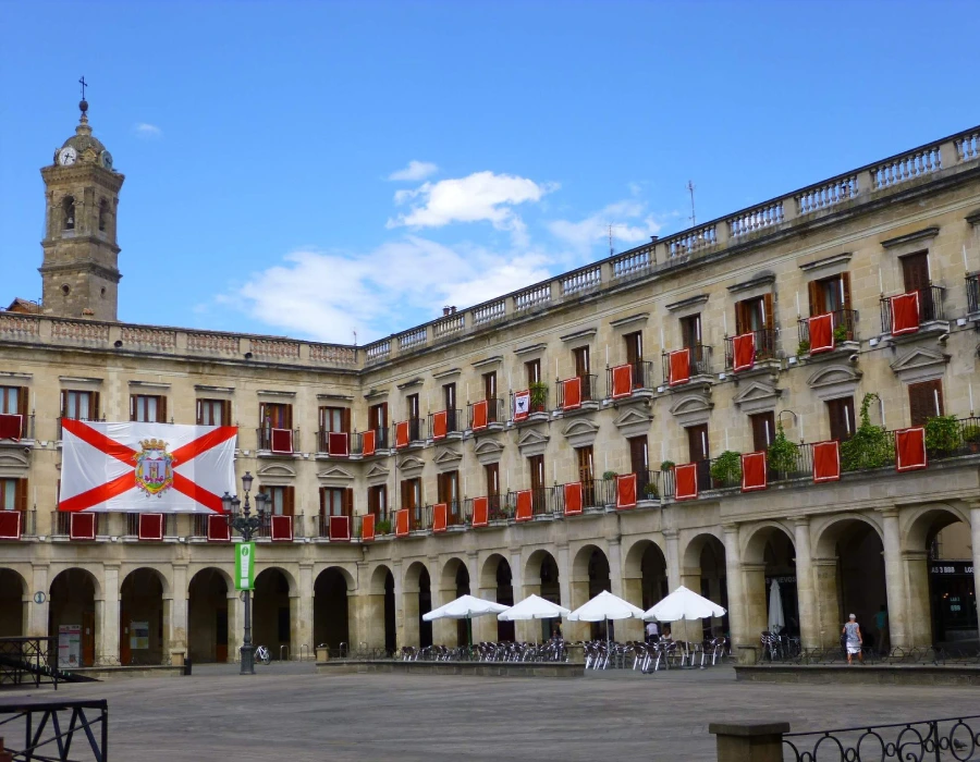 Patio de un edificio hist&oacute;rico con banderas y arcos bajo cielo despejado