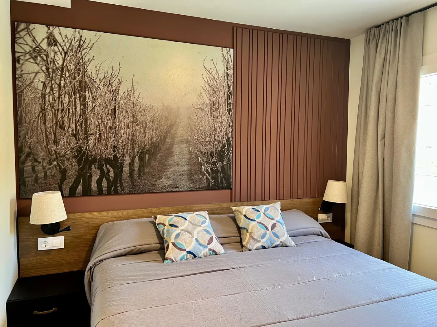 Dormitorio con cama doble, l&aacute;mparas y foto de &aacute;rboles en pared