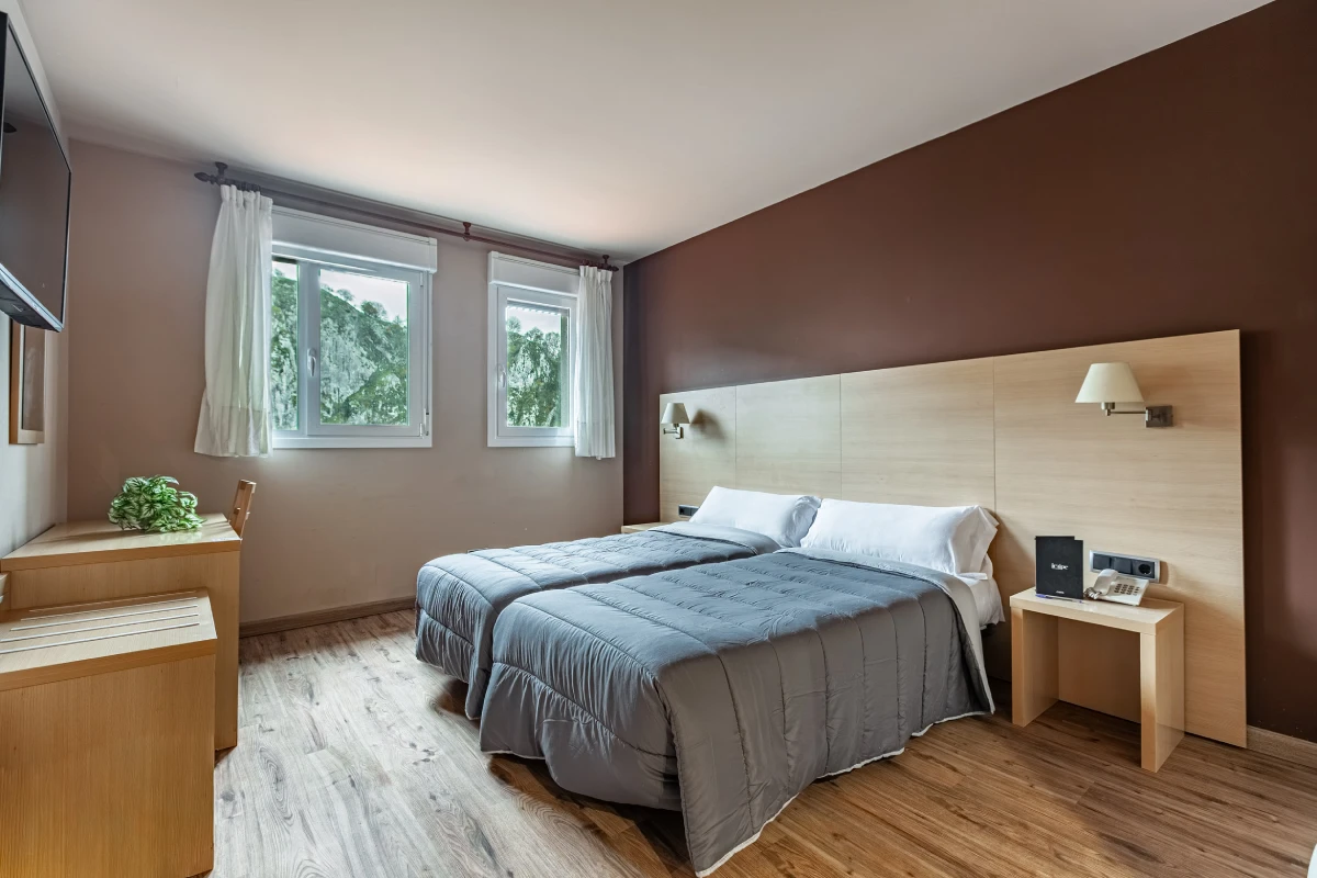 Dormitorio moderno con cama doble, cabecero de madera y cortinas blancas