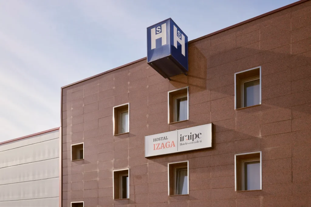 Fachada de hotel con r&oacute;tulos Hostal Izaga e iNripe, y luces en el exterior
