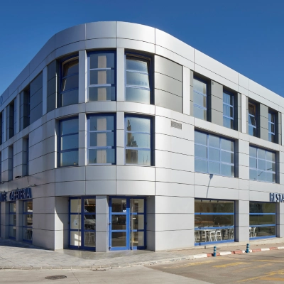 Edificio moderno con fachada blanca y ventanas de cristal azul, vista frontal