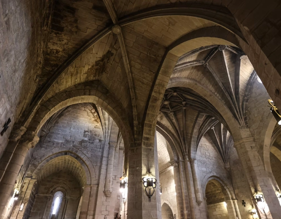 Interior de una catedral con b&oacute;vedas de piedra y arcos ojivales.
