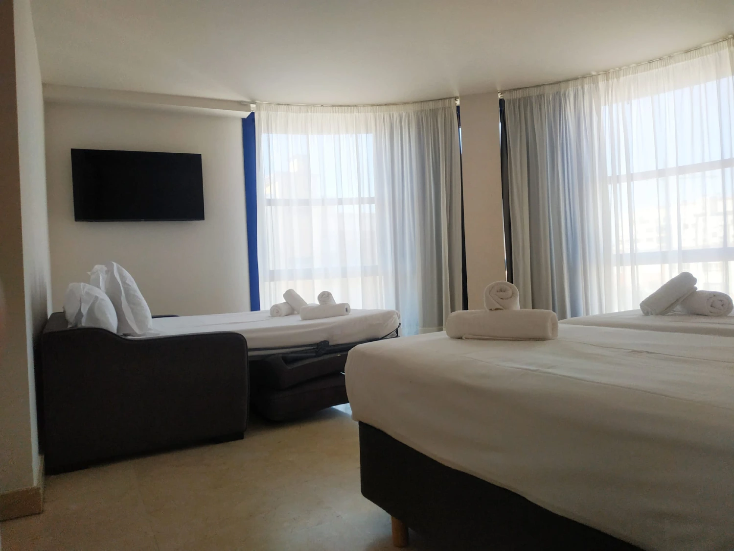 Habitaci&oacute;n de spa con camas dobles, cortinas y toallas dobladas junto a la ventana
