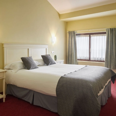 Dormitorio moderno con cama doble y cortinas en ventana.
