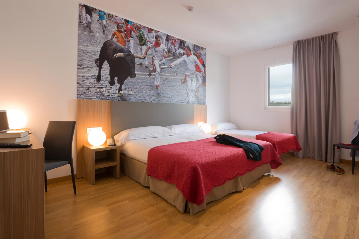 Habitaci&oacute;n moderna con cama doble, l&aacute;mparas y mural de toros en la pared