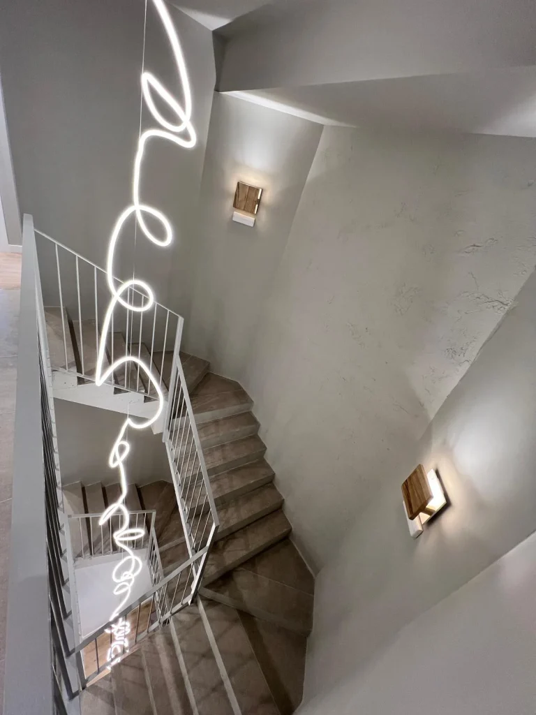 Escalera de hormig&oacute;n con barandas y luces decorativas LED en pared blanca