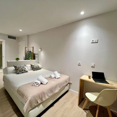 Dormitorio moderno con cama doble y escritorio con laptop