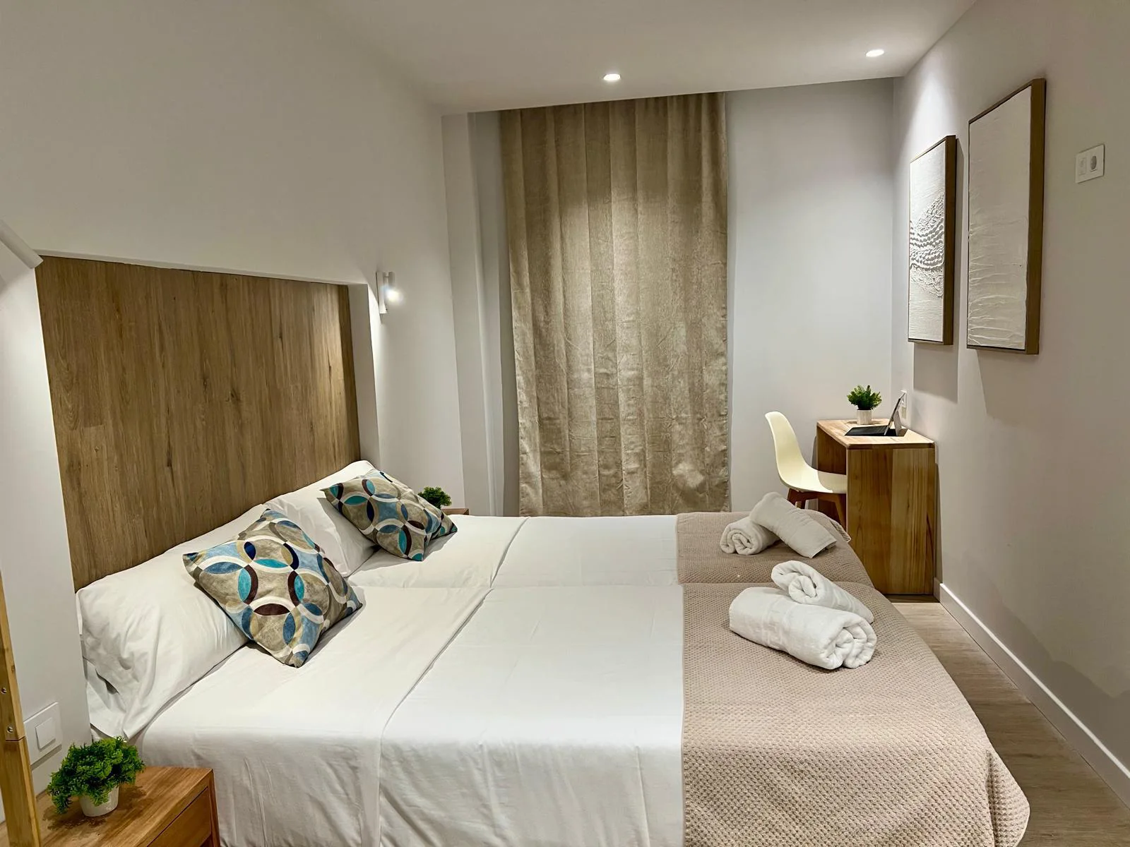 Dormitorio moderno con cama doble, l&aacute;mparas, cortinas y cuadro en la pared.