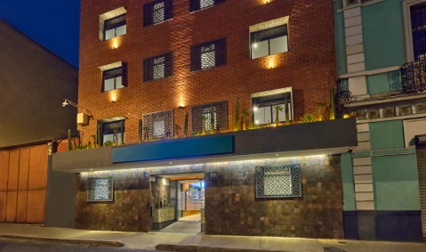 Fachada de ladrillo iluminada de noche con entradas y ventanas.