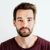 Hombre con barba y cabello corto, con camiseta oscura