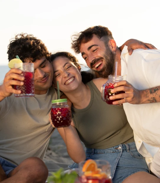 Grupo de amigos brindando con bebidas coloridas y sonrisas al aire libre