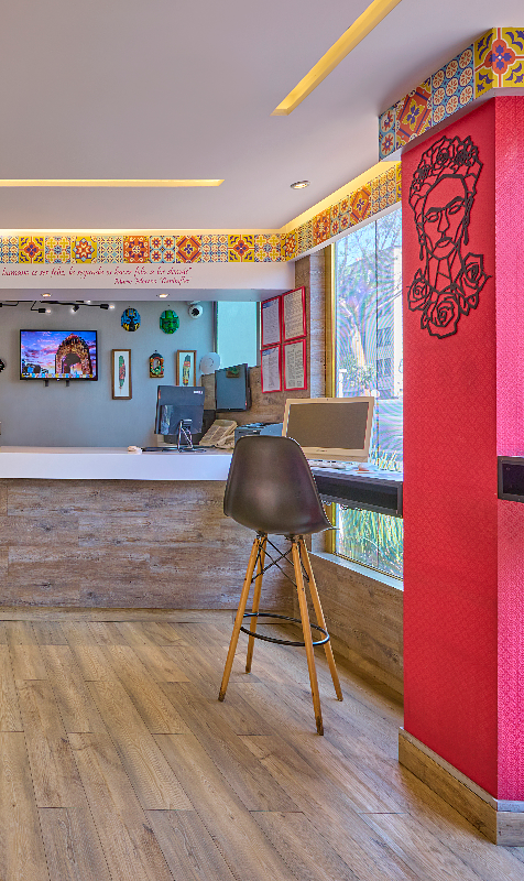 Interior de una cafeter&iacute;a con barra, silla alta y decoraci&oacute;n colorida.