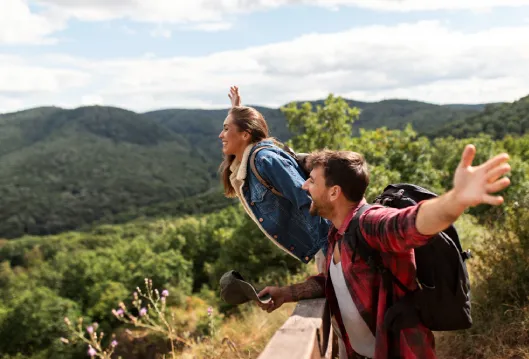 Senderistas con mochila y chaquetas en la monta&ntilde;a, saludando al aire