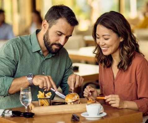 Pareja sonriente comparte comida y bebida en un restaurante al aire libre