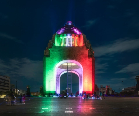Torre iluminada con luces de colores de noche en la plaza.