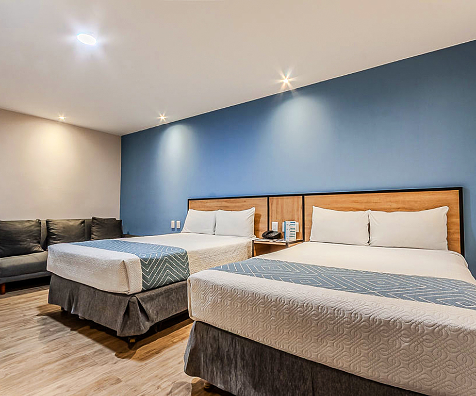 Habitaci&oacute;n doble moderna con camas, cabecero de madera y luces empotradas.