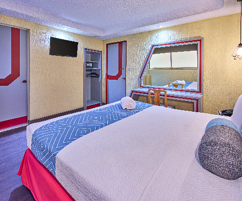 Habitaci&oacute;n de hotel con cama doble, ventana, televisi&oacute;n y almohadas