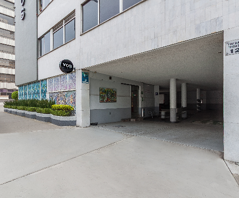 Entrada de edificio moderno con columnas y pared con mosaico.