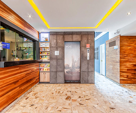 Recepci&oacute;n con puerta y piso de m&aacute;rmol, mostrador y luces amarillas.