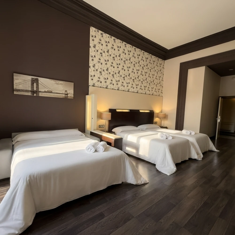 Habitaci&oacute;n de hotel con dos camas, almohadas y decoraci&oacute;n de pared oscura