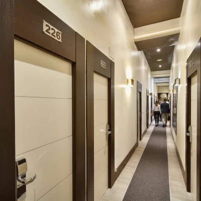 Pasillo de hotel con puertas numeradas y personas al fondo.