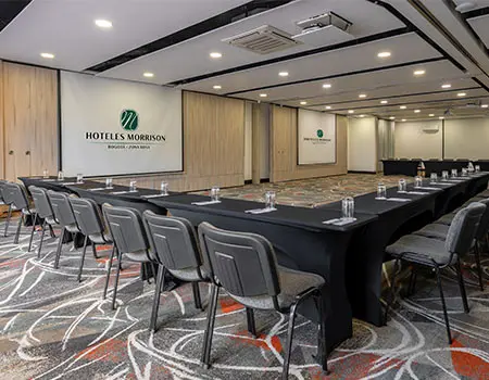 Sala de conferencias con mesas y sillas en un hotel.