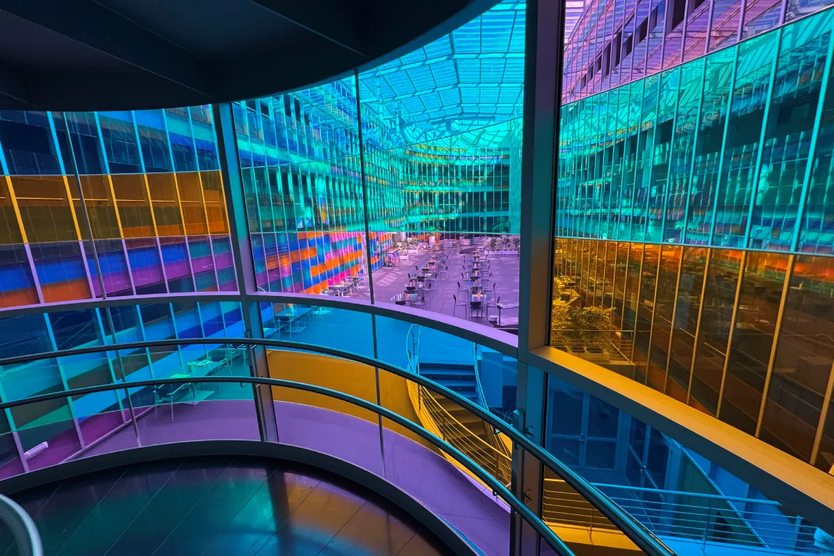 Vista interior de un edificio con pasillo circular y luces neón azules y moradas
