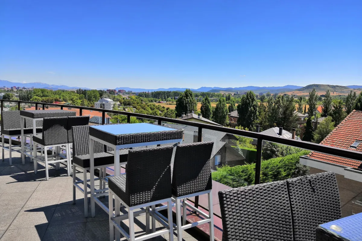 Terraza con mesa y sillas de mimbre, vista a un paisaje y montañas al fondo