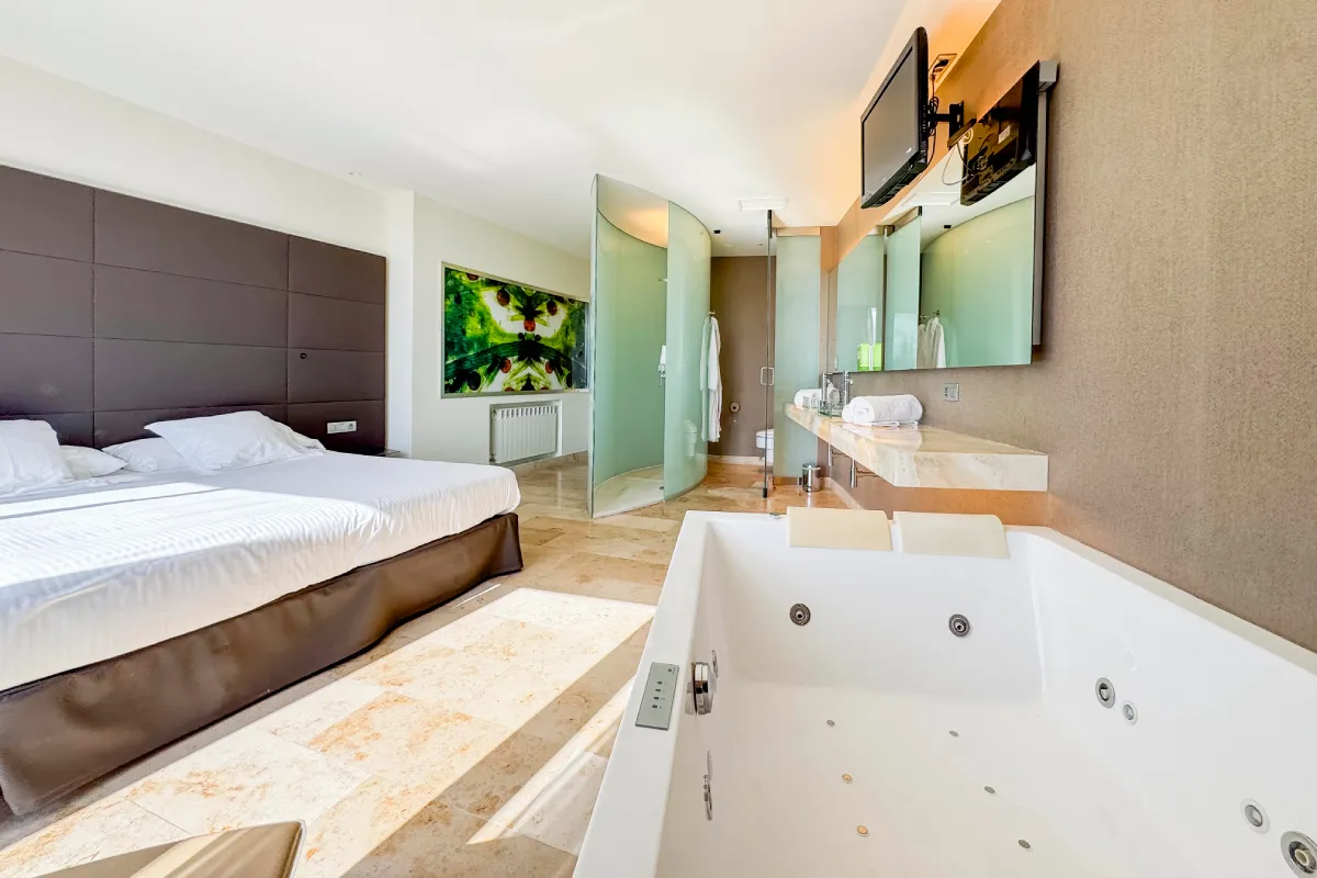 Suite de hotel con cama, bañera de hidromasaje y tocador moderno
